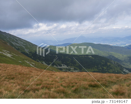 View from grassy hill slopes of hiking trail from Chopok at mountain meadow landscape of ridge Low Tatras mountains Nature park, Slovakia. cloudy late summer day 73149147