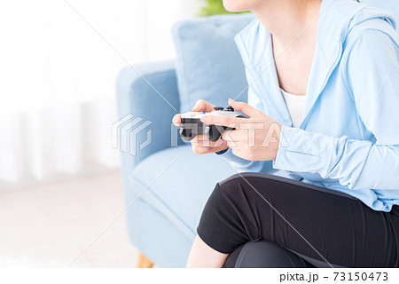 ソファに座ってネットゲームをプレイする女性の手元 73150473