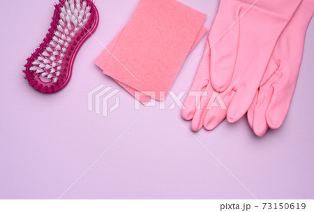 Pink rubber gloves for cleaning, pink sponges, brushes on a purple background Pink rubber gloves for cleaning, pink sponges, brushes on a purple background 73150619