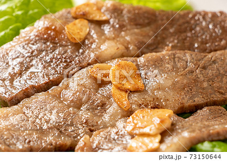 国産黒毛和牛カルビ焼肉 サンチュの上に盛り付け にんにくチップのせ の写真素材