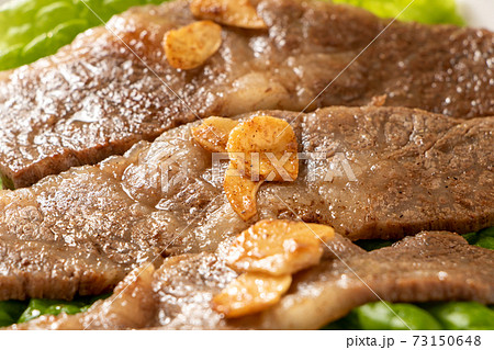 国産黒毛和牛カルビ焼肉 サンチュの上に盛り付け にんにくチップのせ の写真素材