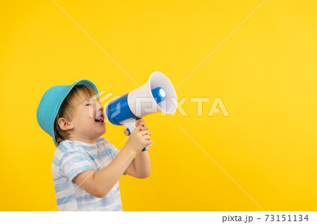 Portrait of kid with loudspeaker against yellow background 73151134