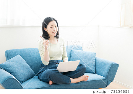 ソファーでパソコンを操作する30代の女性 73154632
