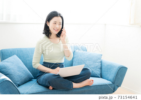 ソファーでパソコンを操作する30代の女性 73154641