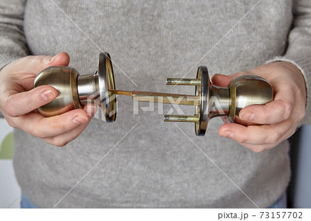 Two pieces of interior door handle in hands of handyman. 73157702