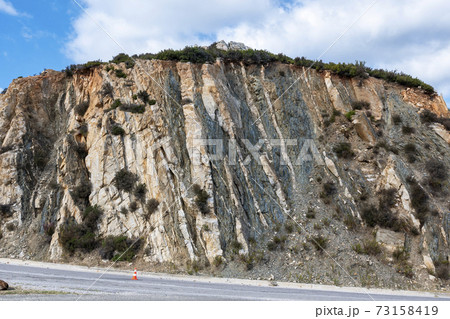 Rocky cliff near the road in Greece 73158419