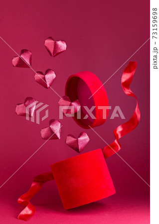 Flying red velvet box with red silk ribbon, red glitter paper hearts fly frome box, vertical Flying red velvet box with red silk ribbon, red glitter paper hearts fly frome box, vertical 73159698