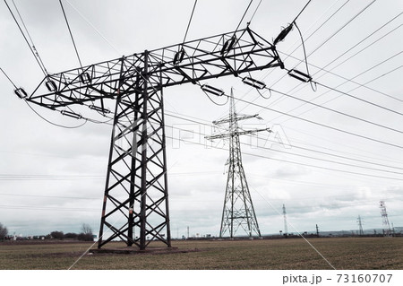 Electricity pylons conducting current from distribution power station, solar renewable energy and grid stability concept, copy space dramatic clouds Electricity pylons conducting current from distribution power station, solar renewable energy and grid stability concept, copy space dramatic clouds 73160707