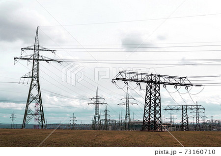 Electricity pylons conducting current from distribution power station, solar renewable energy and grid stability concept, copy space dramatic clouds Electricity pylons conducting current from distribution power station, solar renewable energy and grid stability concept, copy space dramatic clouds 73160710