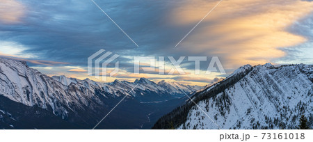 Snow capped Mount Rundle mountain range in beautiful dusk. Sky of red pink clouds in the background. Banff National Park in winter, Canadian Rockies. Beautiful nature scenery. 73161018