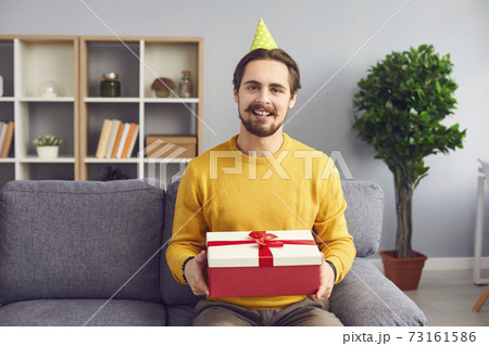 Cheerful man with a gift in his hands remotely congratulates a person on his birthday via webcam. Cheerful man with a gift in his hands remotely congratulates a person on his birthday via webcam. 73161586
