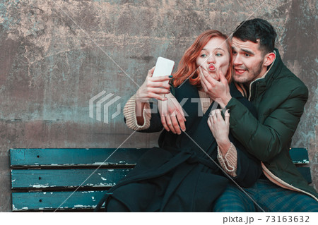 Cheerful Couple Making Selfie on the Bench Cheerful Couple Making Selfie on the Bench 73163632