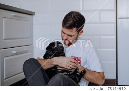 The guy gently hugs a pug dog 73164950