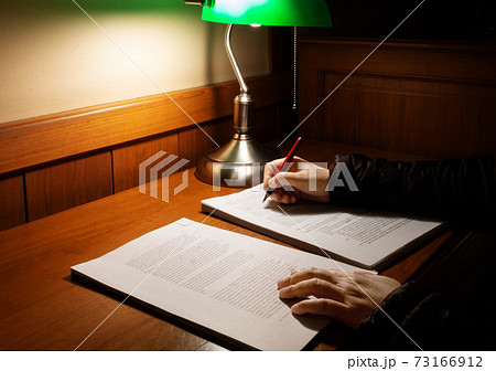 hand holding red pen over blurred proofreading paper on wooden table 73166912