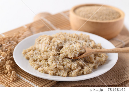 Cooked brown quinoa seeds on white dish with spoon for eating Cooked brown quinoa seeds on white dish with spoon for eating 73168142