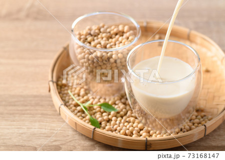 Soy milk pouring into a glass with soybeans 73168147