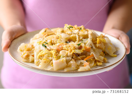 Thai food, Stir fried rice noodles with egg and chicken on dish holding by hand Thai food, Stir fried rice noodles with egg and chicken on dish holding by hand 73168152