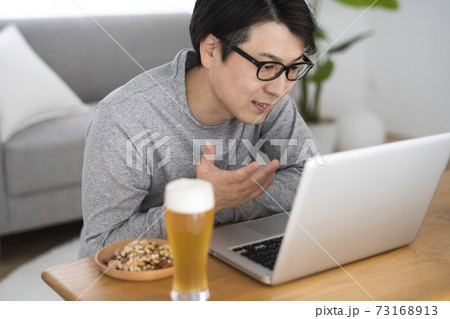 自宅でオンライン飲み会をしている男性 73168913