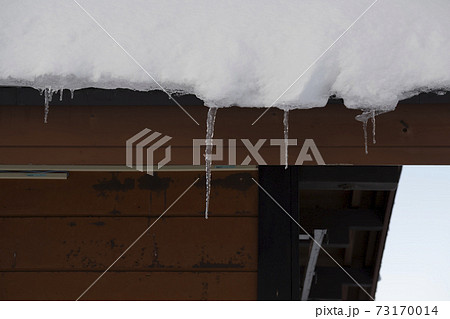 屋根に積もった雪から下がるつらら 屋根に積もった雪から下がるつらら 73170014