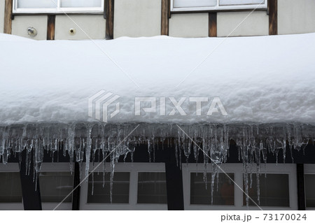 屋根に積もった雪から下がるつらら 73170024