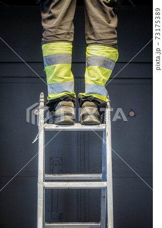 Handyman's foot on the laddem close up worker legs standing on the ladder, selective focus Handyman's foot on the laddem close up worker legs standing on the ladder, selective focus 73175389
