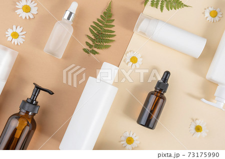 Set of care cosmetics. Various bottles, tubes with cosmetic, chamomile flowers, fern leaves on a beige and brown background. Beauty concept. Top view Flat lay Set of care cosmetics. Various bottles, tubes with cosmetic, chamomile flowers, fern leaves on a beige and brown background. Beauty concept. Top view Flat lay 73175990