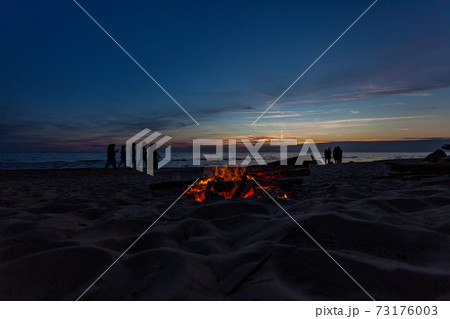 Unrecognisable people celebrating summer solstice with bonfires on beach 73176003