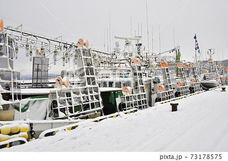 冬の北海道乙部町乙部港で雪の積もったイカ釣り漁船の風景を撮影の写真素材