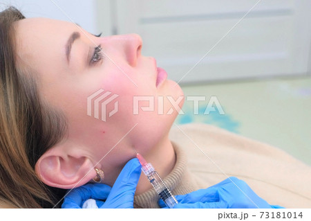 Doctor makes injection with filler in woman face against wrinkles, side view. Doctor makes injection with filler in woman face against wrinkles, side view. 73181014