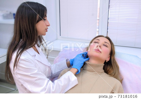 Doctor cosmetologist makes injection with filler in woman face against wrinkles. Doctor cosmetologist makes injection with filler in woman face against wrinkles. 73181016