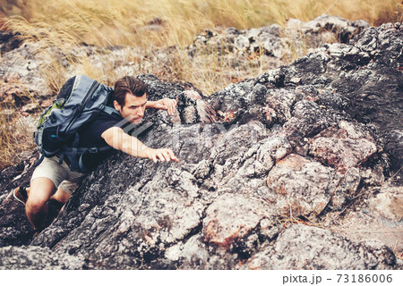 Hiker man climbing natural rocky wall with tropical valley on the background. Hiker man climbing natural rocky wall with tropical valley on the background. 73186006