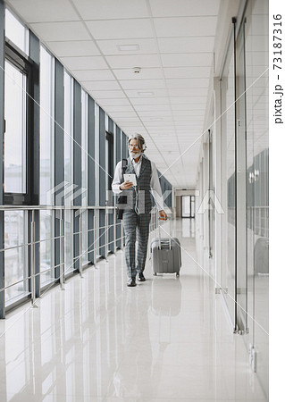 Senior businessman with travel suitcase in airport Senior businessman with travel suitcase in airport 73187316
