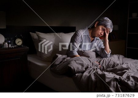 Depressed senior woman sitting in bed cannot sleep from insomnia Depressed senior woman sitting in bed cannot sleep from insomnia 73187629