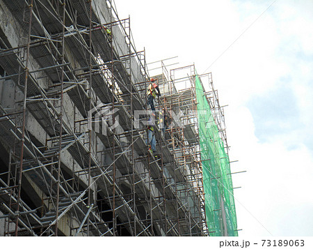 MALACCA, MALAYSIA -MAC 29, 2017: Construction workers used metal scaffolding when working at height at the construction site. They are required to wear the necessary safety equipment to do so. MALACCA, MALAYSIA -MAC 29, 2017: Construction workers used metal scaffolding when working at height at the construction site. They are required to wear the necessary safety equipment to do so. 73189063