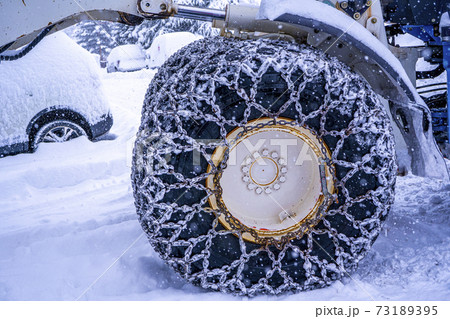 Closeup of a chained wheel of a snowy snow plow on the mountain ski resort in french Alps 73189395