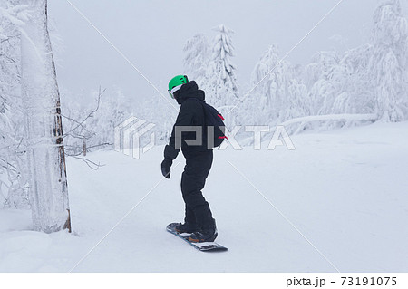 teenage snowboarder going to slide down a mountain along a forest trail in frosty weather teenage snowboarder going to slide down a mountain along a forest trail in frosty weather 73191075