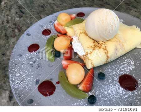 Tasty crepes with fresh strawberries, raspberries, kiwi, melon and ice cream 73191091