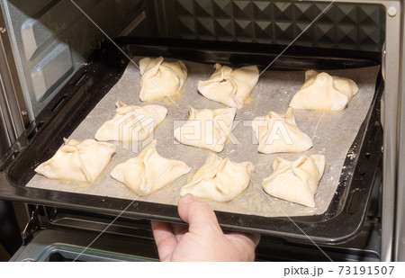 Installing a baking sheet with dessert in the oven. 73191507