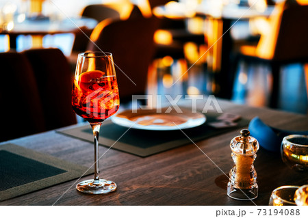 Close upof a glass with ice and orange coctail in restaurant. Close upof a glass with ice and orange coctail in restaurant. 73194088