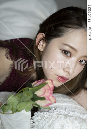 ベッドでくつろぐ女性と花 73196022