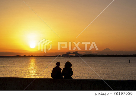 夕焼けの東京ゲートブリッジを眺めるカップルのシルエット 夕焼けの東京ゲートブリッジを眺めるカップルのシルエット 73197056