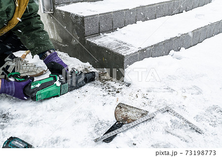 雪降りの中での玄関外階段手摺取り付け工事ベースプレート取り付け 73198773