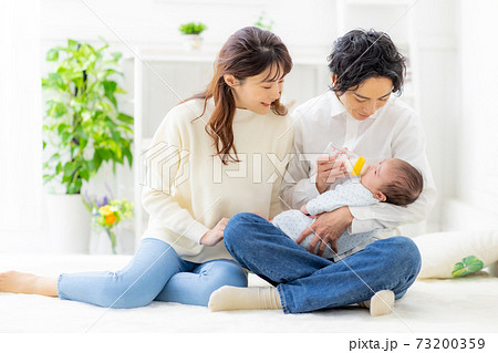 赤ちゃんにミルクをあげる夫婦 73200359