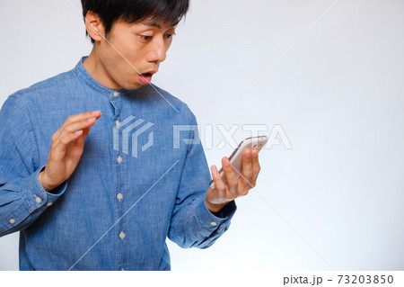スマホを見て驚く男性 73203850