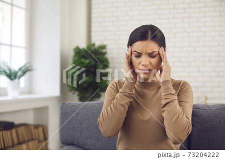 Tired stressed young woman touching her temples, suffering from headache or migraine Tired stressed young woman touching her temples, suffering from headache or migraine 73204222