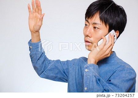 電話をしながら手を挙げる男性　呼び止める 73204257