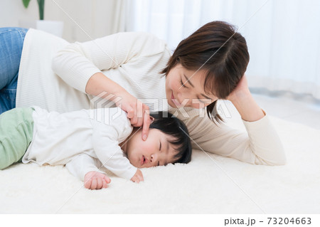 赤ちゃんに添い寝するお母さんの写真素材