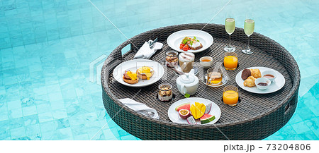 Floating Breakfast tray in swimming pool at luxury hotel or tropical resort villa, fruits; mango, watermelon dragon and passion fruit, food, bread, coffee, tea, wine and orange juice. Exotic summer Floating Breakfast tray in swimming pool at luxury hotel or tropical resort villa, fruits; mango, watermelon dragon and passion fruit, food, bread, coffee, tea, wine and orange juice. Exotic summer 73204806