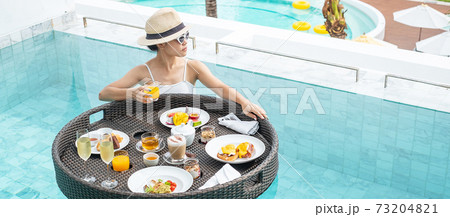 Happy woman in white swimsuit having Floating Breakfast tray in luxury pool hotel, young female with sunglasses enjoy in tropical resort. Relaxing, Exotic summer travel, holiday, vacation and weekend Happy woman in white swimsuit having Floating Breakfast tray in luxury pool hotel, young female with sunglasses enjoy in tropical resort. Relaxing, Exotic summer travel, holiday, vacation and weekend 73204821