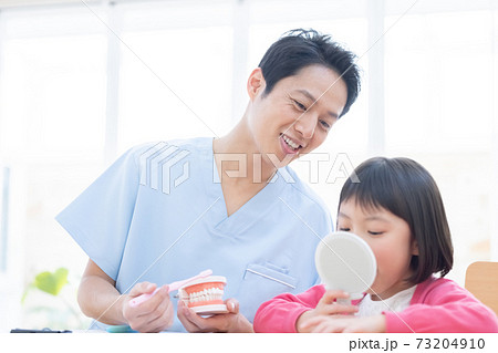 歯医者 歯磨き指導を受ける女の子と医師の写真素材